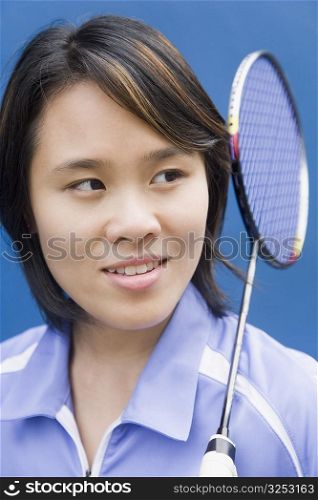 Close-up of a young woman with a badminton racket and smiling