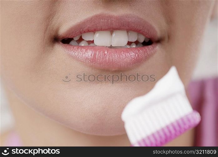 Close-up of a young woman with a toothbrush in front of her mouth