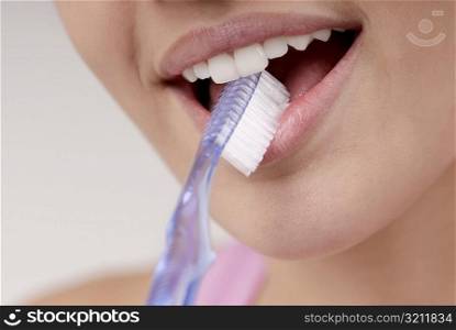 Close-up of a young woman with a toothbrush in her mouth
