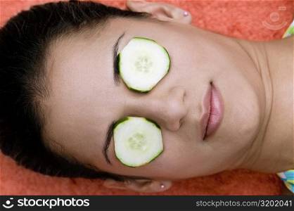 Close-up of a young woman with cucumber slice on her eyes