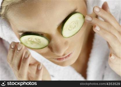 Close-up of a young woman with cucumber slices on her eyes