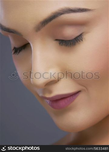 Close-up of a young woman with eyes closed over colored background
