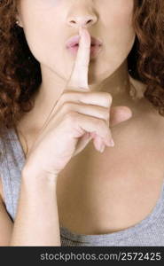 Close-up of a young woman with her finger on her lips