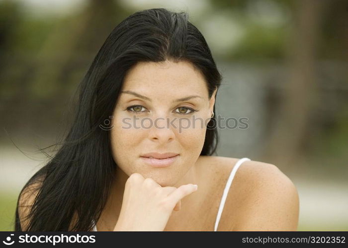 Close-up of a young woman with her hand under her chin