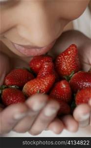 Close-up of a young woman with strawberries in her hands