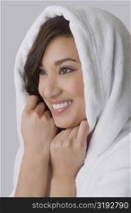 Close-up of a young woman wrapped in a towel and smiling