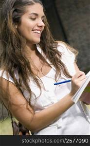 Close-up of a young woman writing and smiling