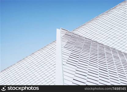 Close up of abstract geometric structure white wall and roof top against blue sky .