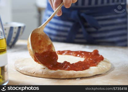 Close Up Of Adding Tomato Sauce To Pizza Base