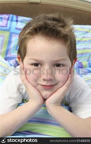 Close up of adorable five year old boy laying in bed.