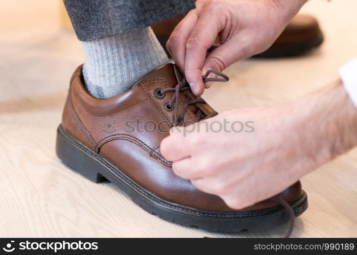 Close Up Of Adult Son Helping Senior Man Tie Shoelaces