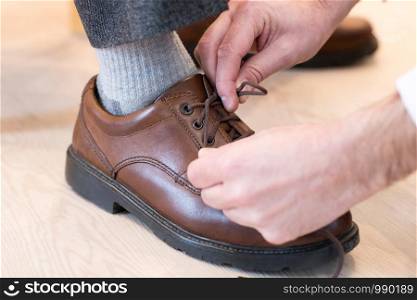 Close Up Of Adult Son Helping Senior Man Tie Shoelaces