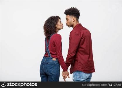 Close-up of African American young couple kissing over white background studio.. Close-up of African American young couple kissing over white background studio