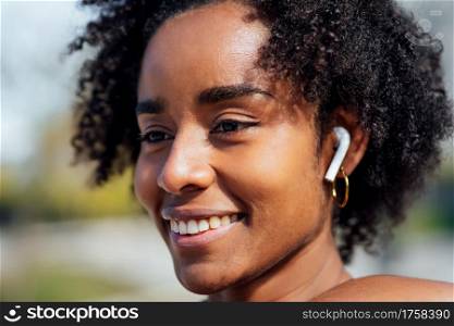 Close-up of afro athletic woman smiling while standing outdoors on the street. Sport and healthy lifestyle.
