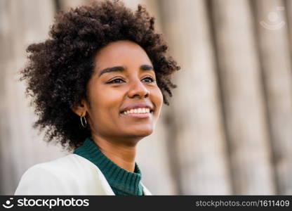 Close up of afro business woman smiling while standing outdoors on the street. Business and urban concept.