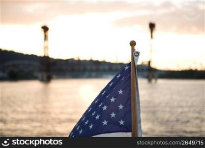 Close-up of American flag on boat, at sunset, a river is visible behind it.