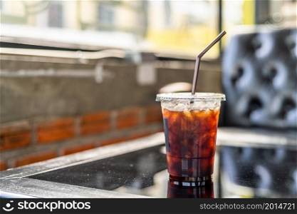 Close-up of Americano ice coffee or black coffee in cup mug on glass wood desk office desk in coffee shop at the cafe,during business work concept