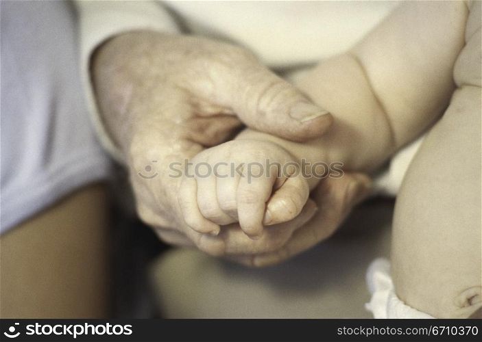 Close-up of an adult&acute;s hand holding a baby&acute;s hand