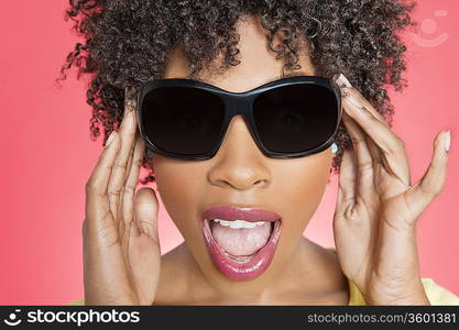 Close-up of an African American woman wearing sunglasses over colored background