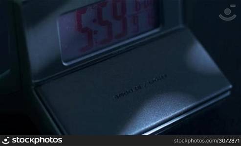 Close up of an alarm clock going off and a hand snooze it