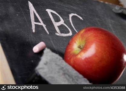 Close-up of an apple and a duster on a blackboard