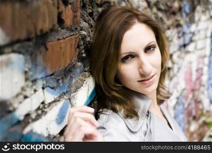 Close-up of an attractive young woman leaning against a concrete wall