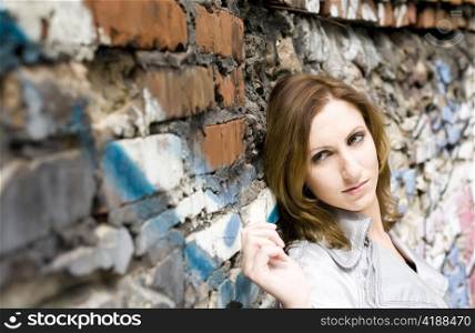 Close-up of an attractive young woman leaning against a graffiti painted wall