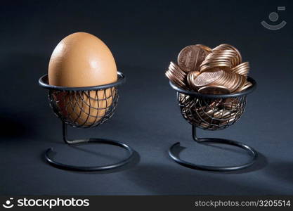 Close-up of an egg and coins in two egg cups