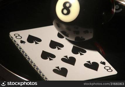 Close-up of an eight ball with a playing card on a pool table