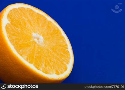 Close-up of an orange cut in half on a blue background. Free space for text.. Close-up of an orange cut in half on a blue background. Free space for text