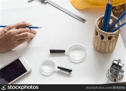Close up of Architect sketching a construction blueprint project with drawing accessories at workplace. Engineer worker drafting at construction site for house building by professional skill.