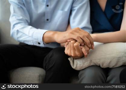 Close-up of Asian couple join hand give to encourage while sitting on the couch in the room to consult mental health problems by doctor. Health and illness concepts