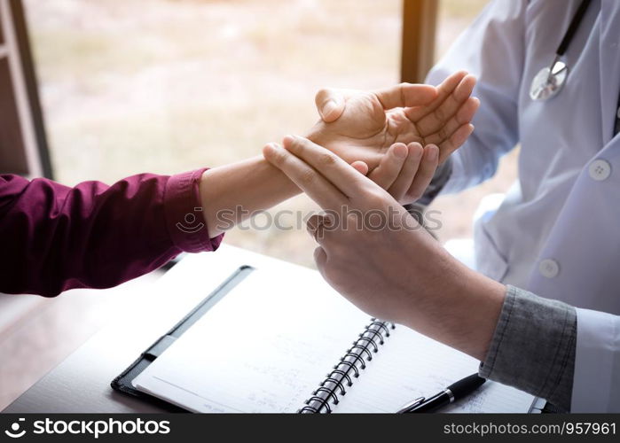 Close up of asian doctor male with medical practitioner taking a patient pulse at clinic room.