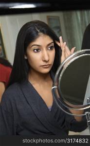 Close up of Asian/Indian young woman looking in mirror primping.
