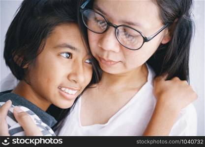 Close-up of Asian mother and daughter hugging each other with love in the room at her home
