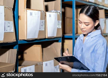 Close up of Asian smart businesswoman working with product inventory in distribution warehouse. For business warehouse inventory and logistic concept.