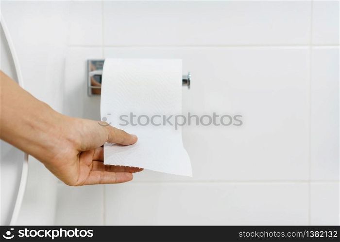 Close up of Asian woman hand pulling paper in bathroom