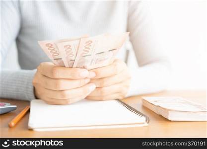 Close up of asian woman with calculator counting money.Woman calculate the spending at home.