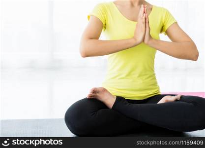 Close-up of Asian women workout practicing yoga training put in yellow dress and practice meditation wellness lifestyle and health fitness concept in a gym,Copy space