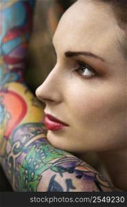 Close-up of attractive Caucasian woman&acute;s face and tattooed arm.