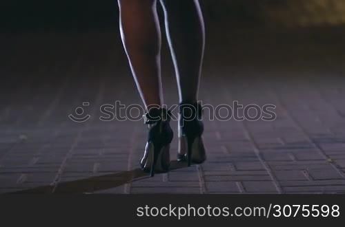 Close up of attractive woman&acute;s legs on high heel shoes dancing on the night city street.