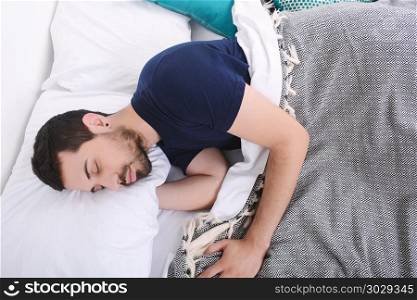 Close-up of attractive young man sleeping on her bed. Indoors.. Man sleeping on bed.
