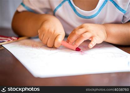 Close up of baby boys hands crayon drawing at dining room table
