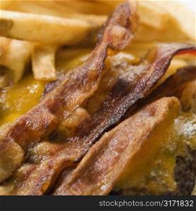 Close up of bacon cheeseburger with french fries.
