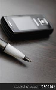 Close-up of ball point pen with a mobile phone