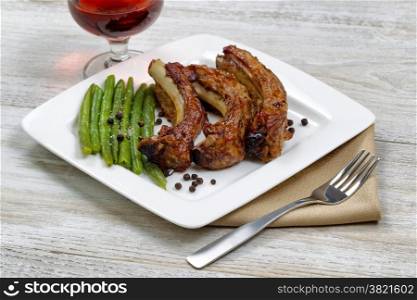 Close up of barbecued pork spare ribs, green beans and red wine ready for eating