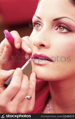 Close up of beautician creating makeup for a young women in the beauty parlour.