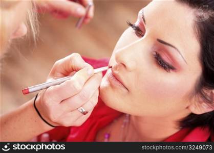 Close up of beautician creating makeup for a young women in the beauty parlour.