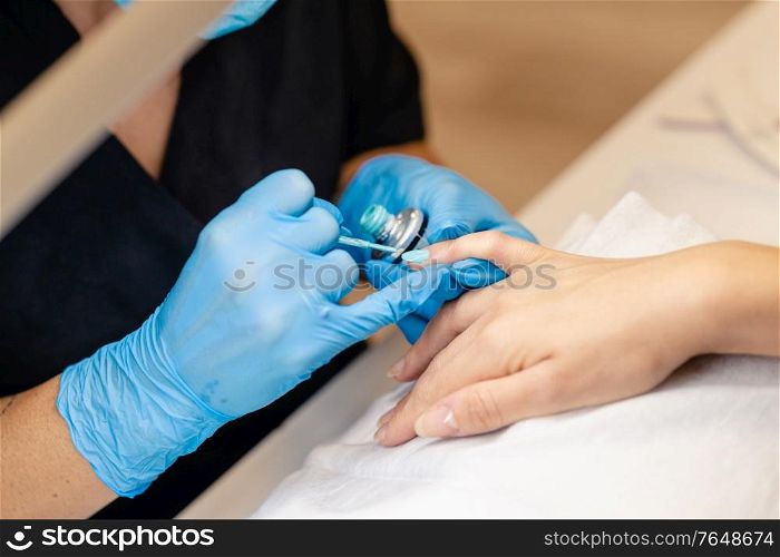 Close-up of Beautician painting her client&rsquo;s nails in blue and yellow nail varnish in a beauty centre. Close-up of Beautician painting her client&rsquo;s nails in blue and yellow nail varnish.