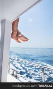 Close-up of beautiful female legs with a bracelet with shells on a yacht, sailing on a yacht, summer vacation, conceptual image of pleasure and enjoyment. Vacation, sea and ocean rest. Close-up of beautiful female legs with a bracelet with shells on a yacht, sailing on a yacht, summer vacation, conceptual image of pleasure and enjoyment. Vacation, sea and ocean rest.